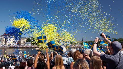 Menschen schwenken Schweden-Flaggen und blaue und gelbe Luftballons steigen in den Himmel  Ola Ericson_imagebank.sweden.se Foto: Ola Ericson